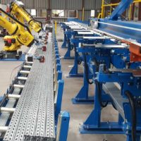 Table de conditionnement avec convoyeurs à taquets et robots de déchargement
